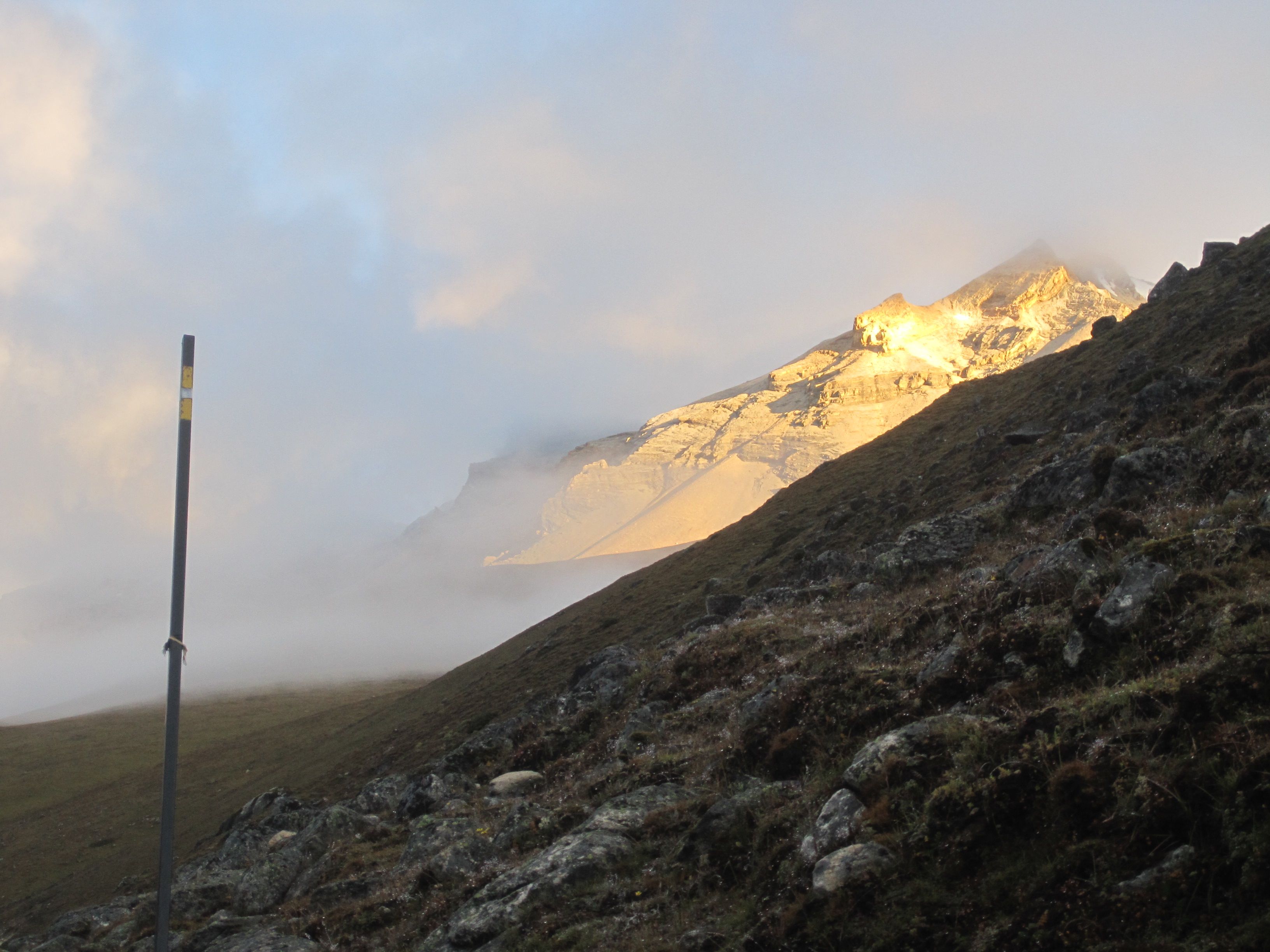 First sunrays with path marker (snow) in the foreground