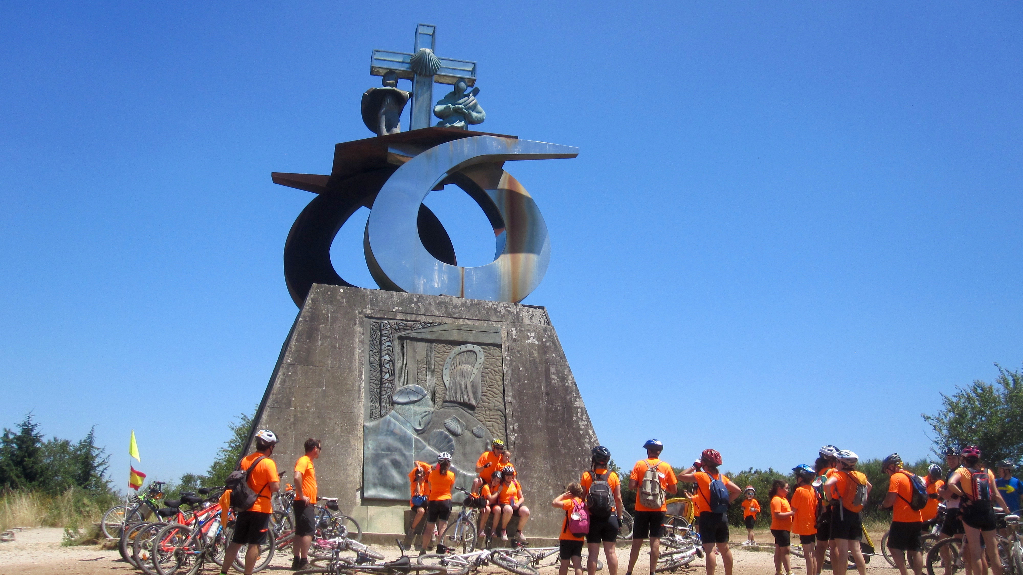 Modern religious sculpture on Monte do Gozo with a group of bikers in front of it